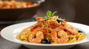 Mediterranean shrimp pasta roni with olives, cherry tomatoes, and feta cheese on a white plate.